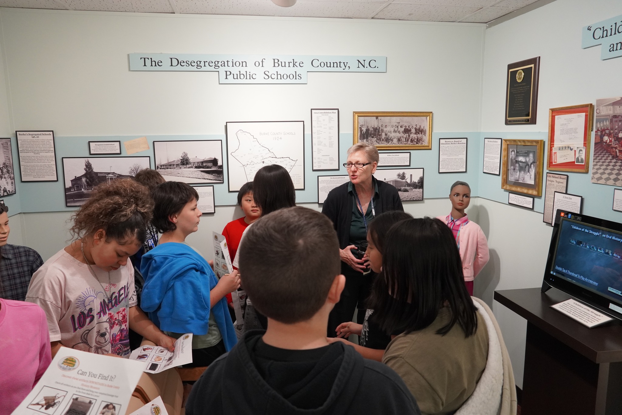 Photo of History Museum docent providing tour of the Children of the Struggle exhibit to group of elementary school students.